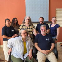 group portrait of teaching faculty, some wearing blue UC-AFT t-shirts