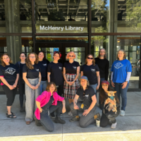 Members of UC-AFT in blue shirts standing outside McHenry library.