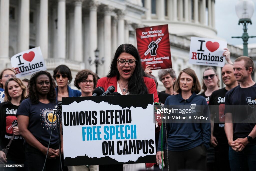 Congresswoman Rashida Taleb addresses a press conference at the capital with a crowd of union educators behind her.