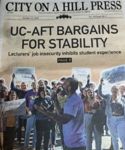 A photograph of the cover of the Oct. 24, 2019 issue of "City on A Hill press - the Student Weekly at UC Santa Cruz." The headline on the cover reads "UC-AFT Bargains For Stability - Lecturers' job insecurity inhibits student experience - page 8." The image on the cover is of lecturer Josh Branhinsky addressing a crowd of students holding signs at a rally.