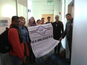 Lecturers carrying a banner that reads "The UC Works Because We do" with hundreds of members' signatures outside an administrator's office at UC Merced in 2019.