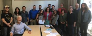 a group of 16 people pose smiling in a conference room.