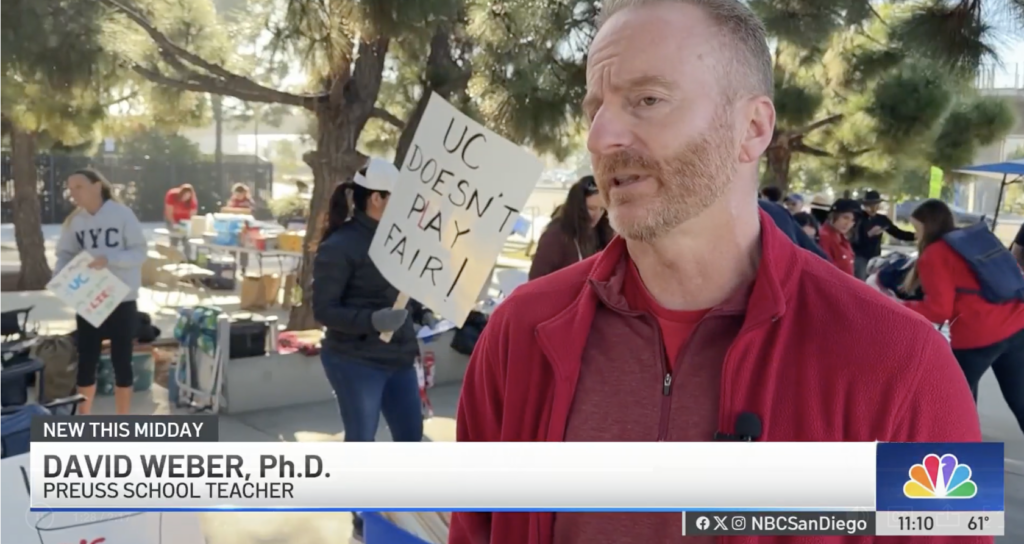 A bearded man wearing red is interviewed by the local NBC news affiliate